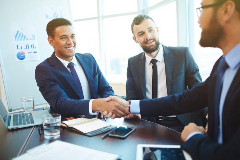 Hombres de negocios en una reunión dándose la mano por haber alcanzado un acuerdo