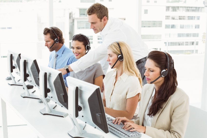 Vista lateral de jóvenes empresarios con auriculares que usan ordenadores en la oficina